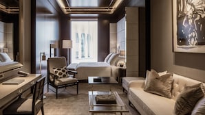 A modern hotel room with a large bed, a sitting area with a sofa and armchair, a desk, and a coffee table. - Four Seasons Hotel London at Tower Bridge (London)
