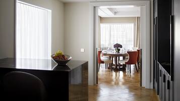 A modern kitchen with a dining area, wooden flooring, and a view to the dining room.