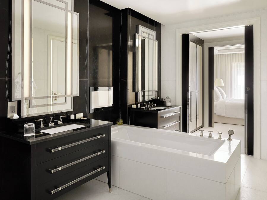 Une salle de bain moderne avec un grand miroir, une baignoire et un meuble-lavabo doté de tiroirs.