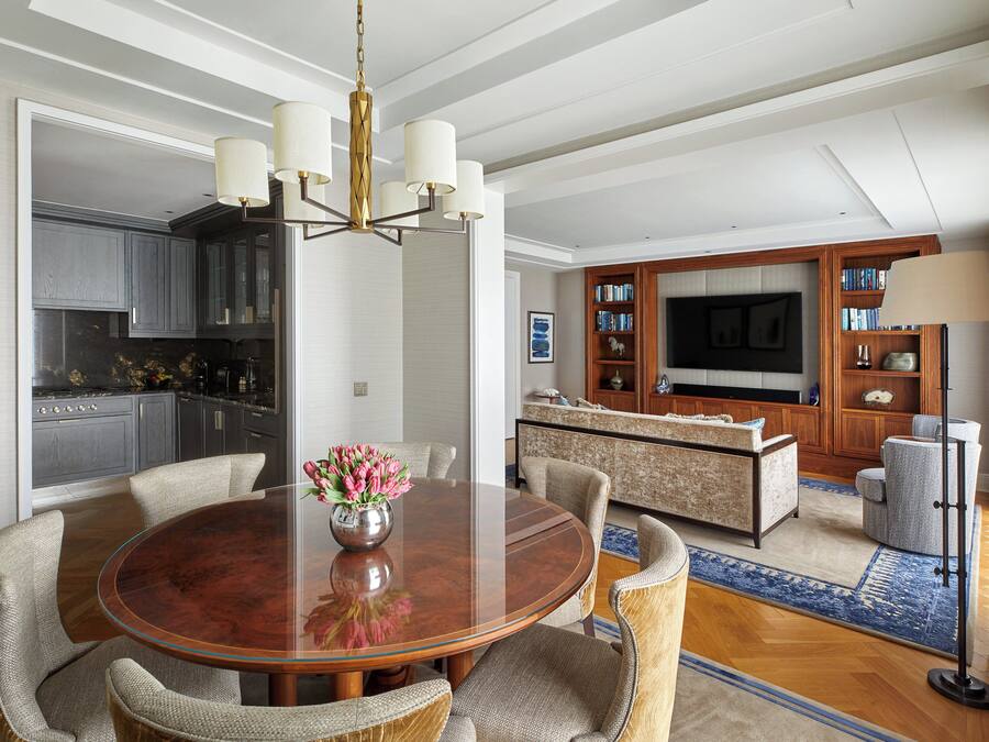 A modern kitchen with dark cabinets, a central island, and a dining area with a round table and chairs.