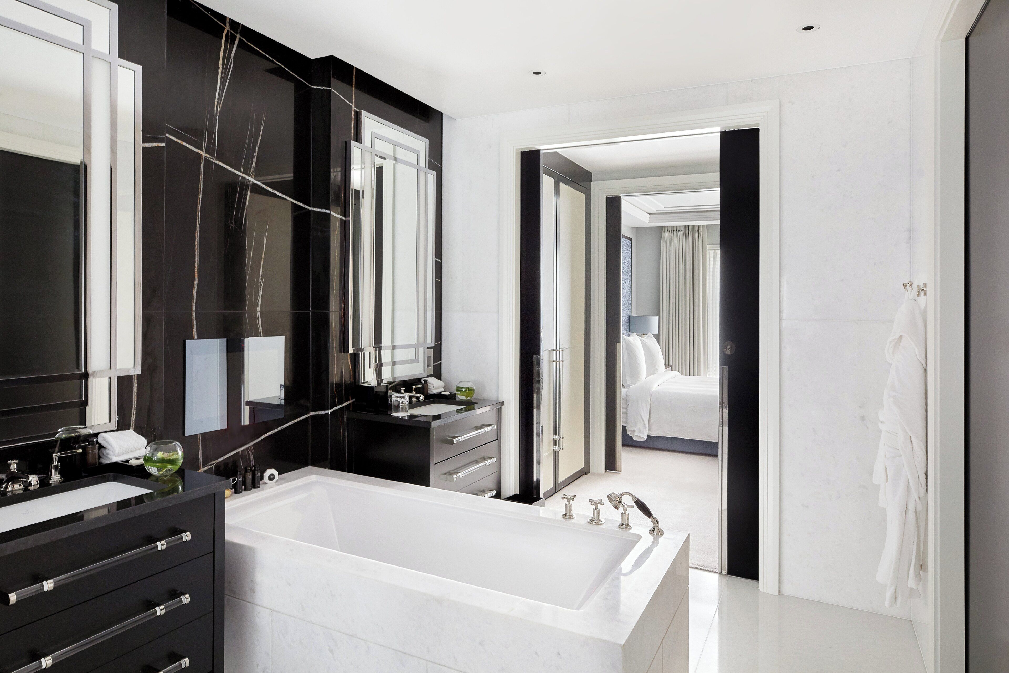 A modern bathroom with a large bathtub, dark cabinetry, and a mirror.
