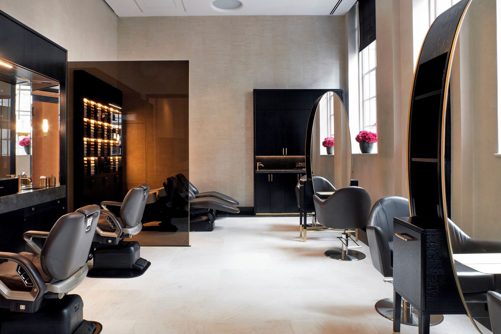 Un intérieur de salon moderne, doté de plusieurs fauteuils de coiffure, d’un grand miroir et d’un espace coiffeuse bien éclairé.