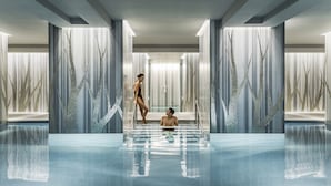 Una piscina interior moderna con diseño minimalista, que cuenta con una zona de trampolín central y dos piscinas laterales.