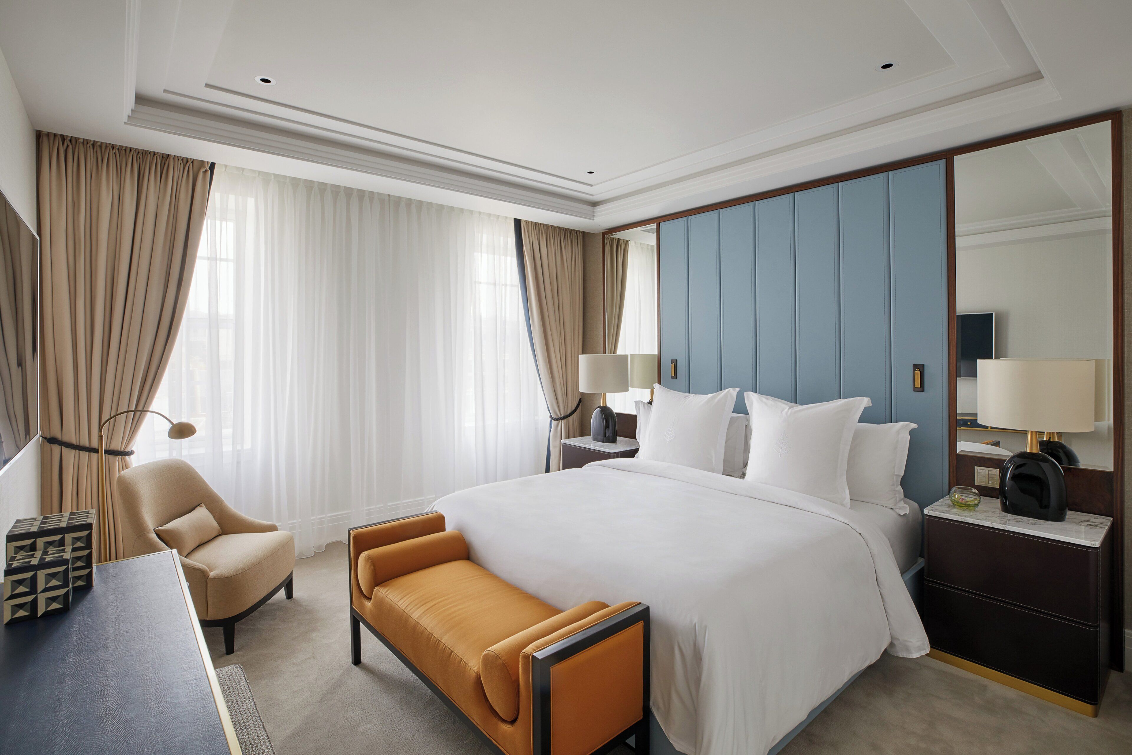 A hotel room with a large bed, a sofa, a desk, and a nightstand with lamps.