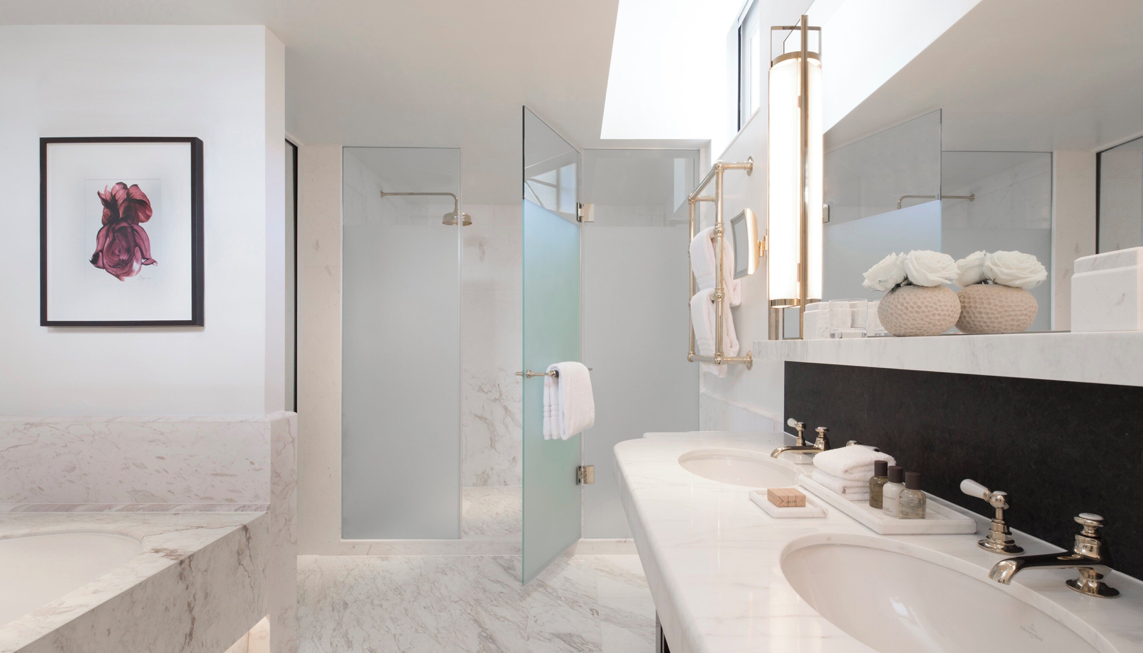 A modern bathroom with a glass-enclosed shower, marble countertops, and a large mirror.