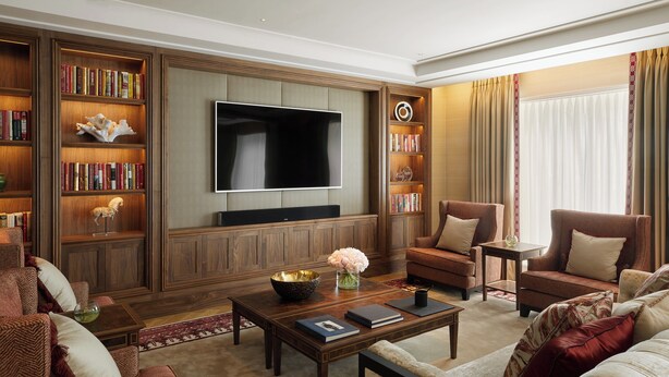 A spacious living room with a large flat-screen TV, wooden bookshelves, and comfortable seating. - Four Seasons Hotel London at Tower Bridge (London)