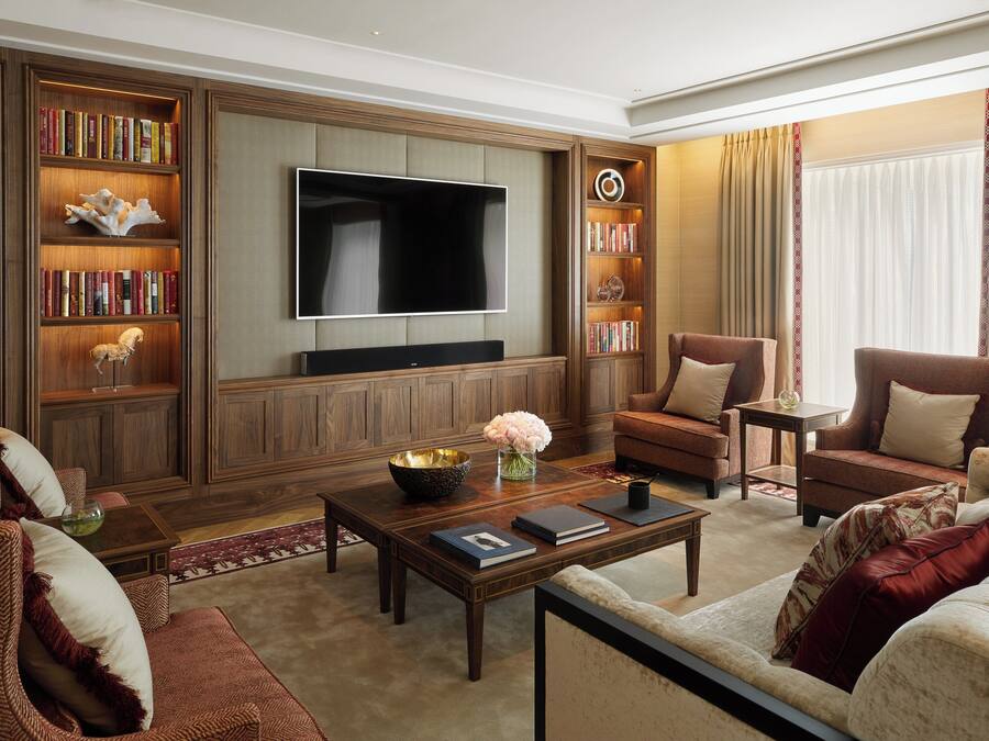 A spacious living room with a large flat-screen TV, wooden bookshelves, and comfortable seating.