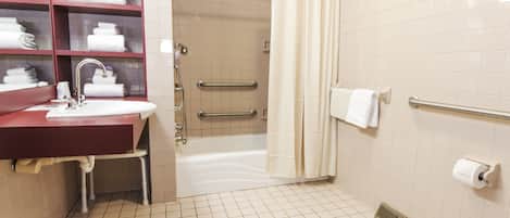 A bathroom with a sink, mirror, shelves with towels, a shower, and a toilet.