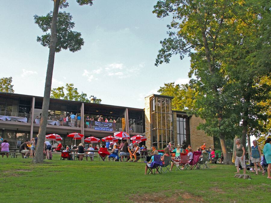An outdoor dining area with tables and chairs, umbrellas, and a building in the background.