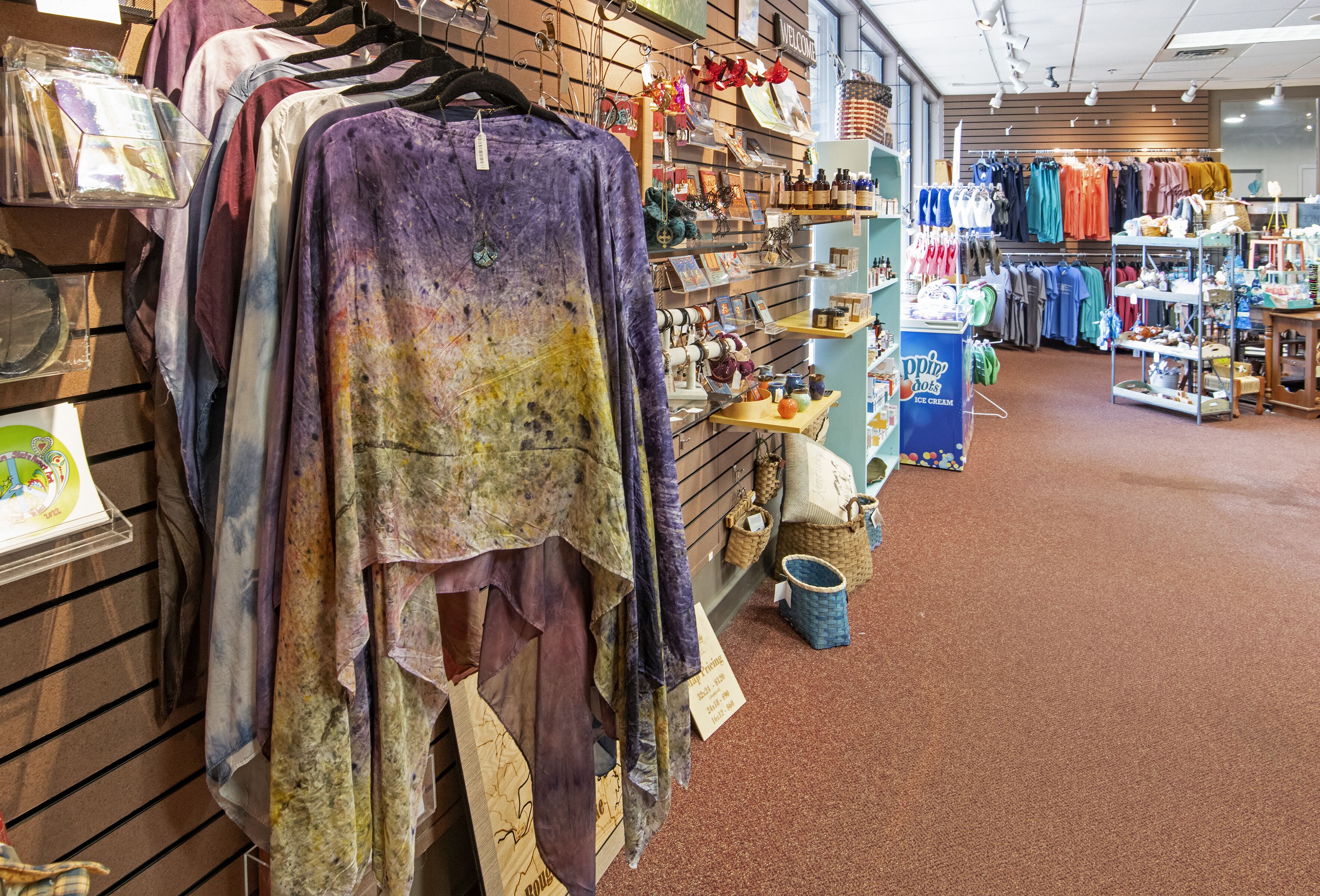 Una tienda de ropa con perchas llenas de prendas coloridas y estantes con accesorios.