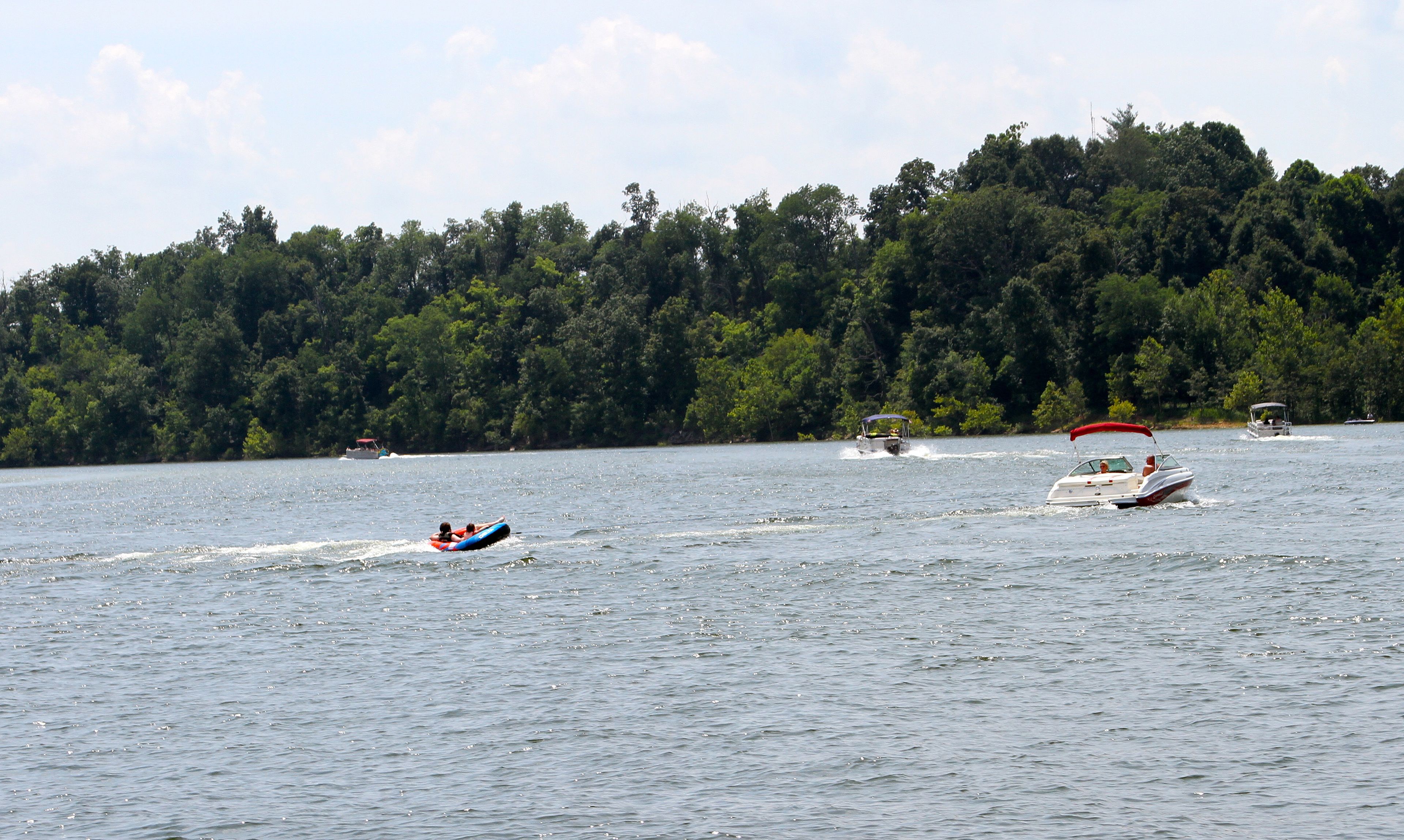 A lake with boats and a person on a tube.