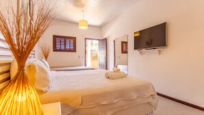 A bedroom with a bed, a TV mounted on the wall, and a door leading to another room.
