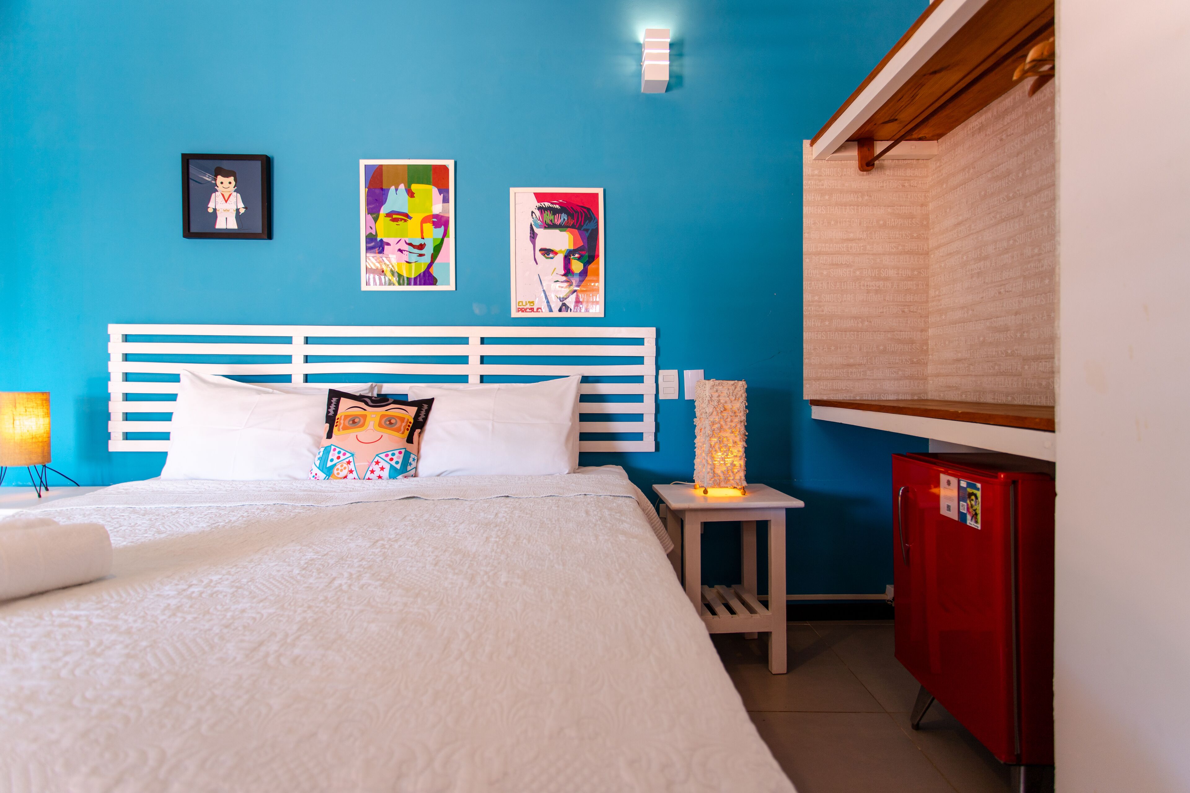 A bedroom with a blue wall, a white bed, and a red cabinet.