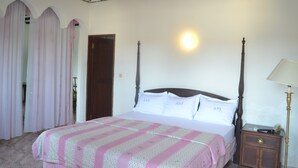Un dormitorio con cama, cortinas, mesita de noche y lámpara.