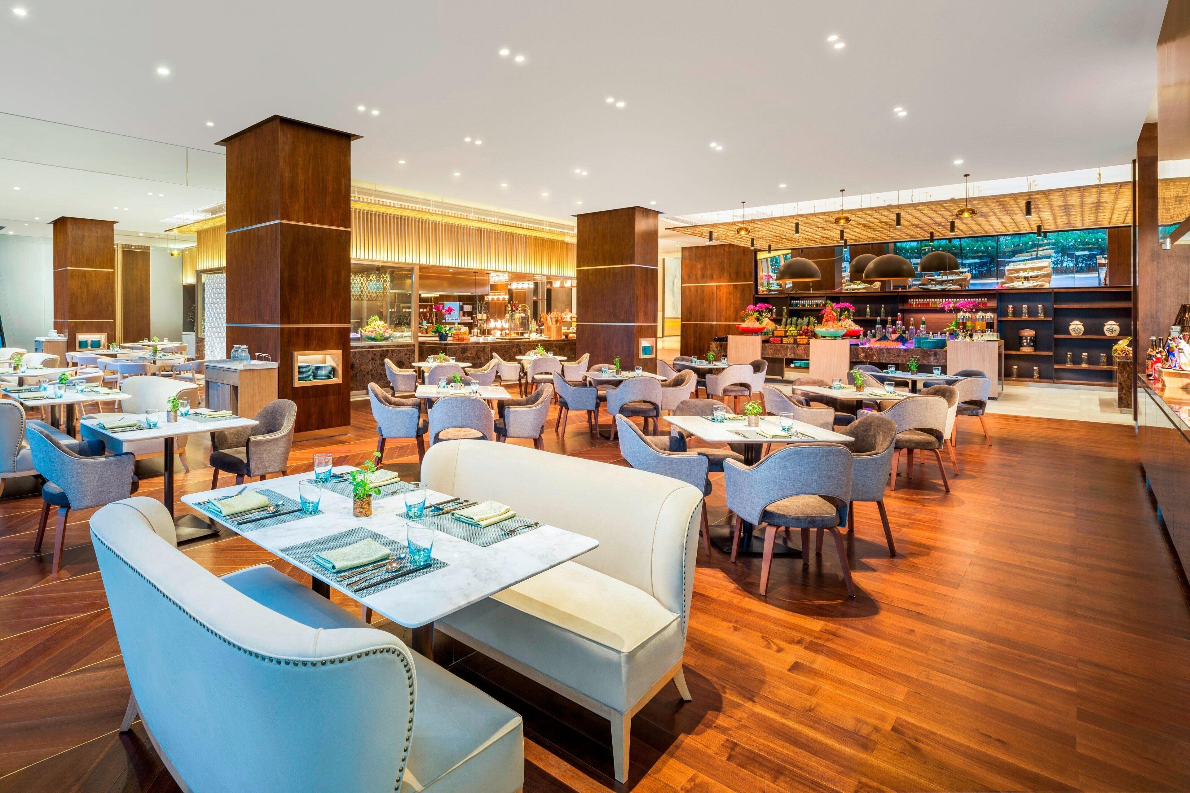 Un restaurant spacieux doté de plusieurs espaces de restauration, d’un plancher en bois et de différents types de sièges, notamment des tables et des banquettes.