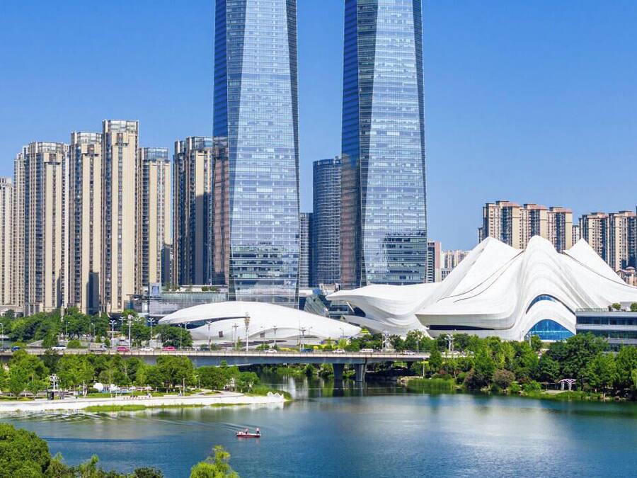 Paisaje urbano con rascacielos modernos y una estructura arquitectónica blanca distintiva cerca del agua.