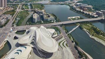 Una estructura arquitectónica moderna con un diseño único y fluido, rodeada por un río y desarrollo urbano.