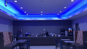 Uma área de bar moderna com assentos, uma máquina de café e um dispensador de água.