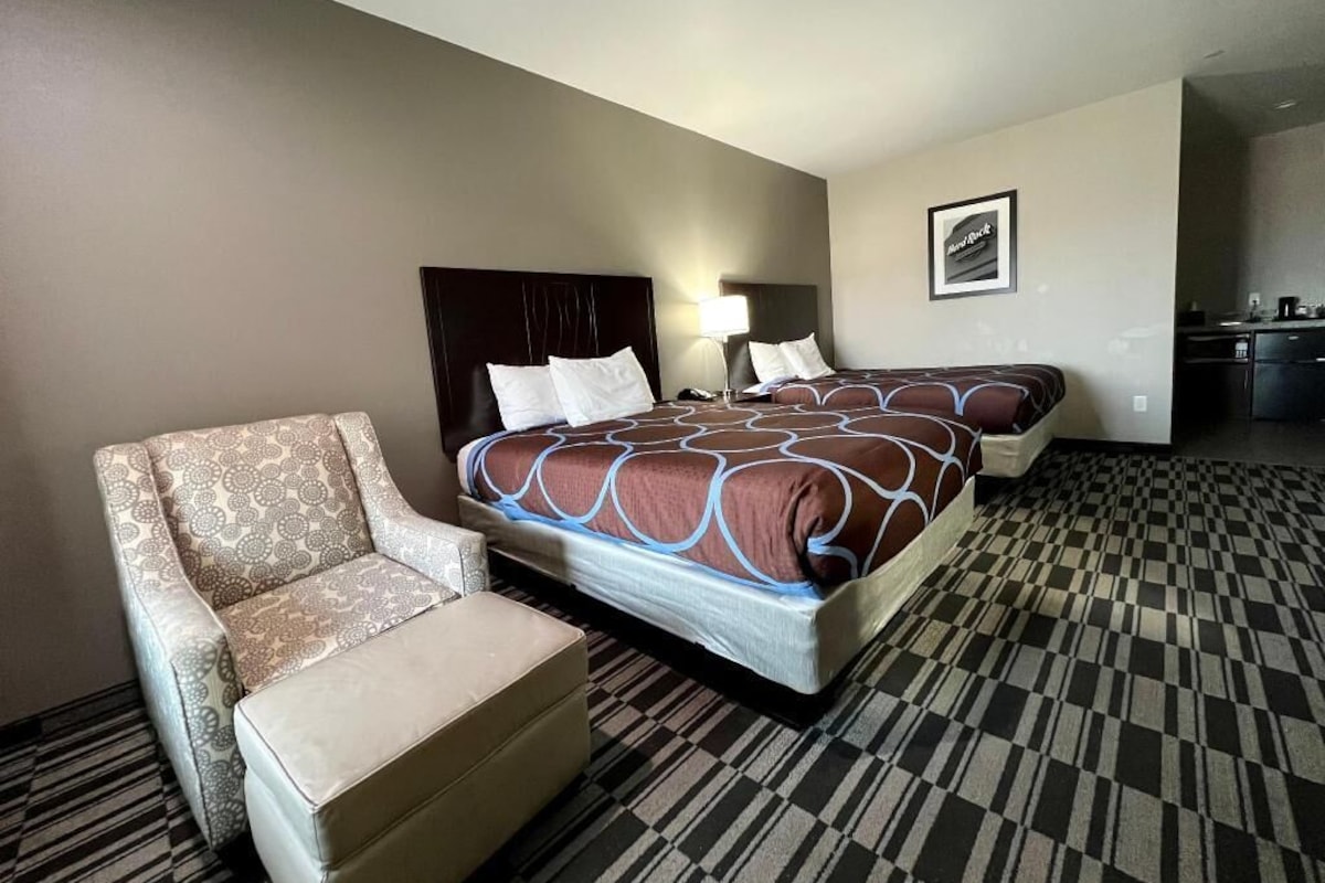A hotel room with a bed, a chair, a desk, and a kitchenette.