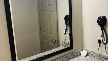 Un baño con un espejo grande, un lavabo y dos secadores de pelo en la pared.