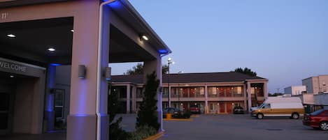 A hotel with a 'WELCOME' sign, a covered parking area, and a building with multiple balconies.