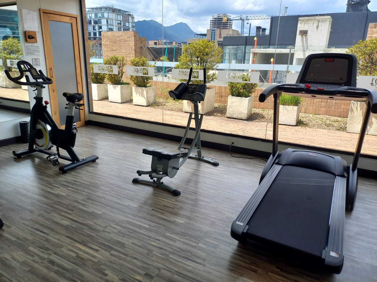 A gym with a treadmill, stationary bike, and elliptical machine.