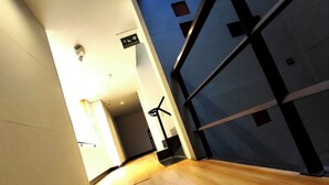 A corridor with a wooden floor, a ceiling-mounted light fixture, and a door with a black handle. - Hotel Scala 68 (Bogotá)