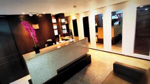 A reception area with a reception desk, seating area, and a view of the interior space. - Hotel Scala 68 (Bogotá)