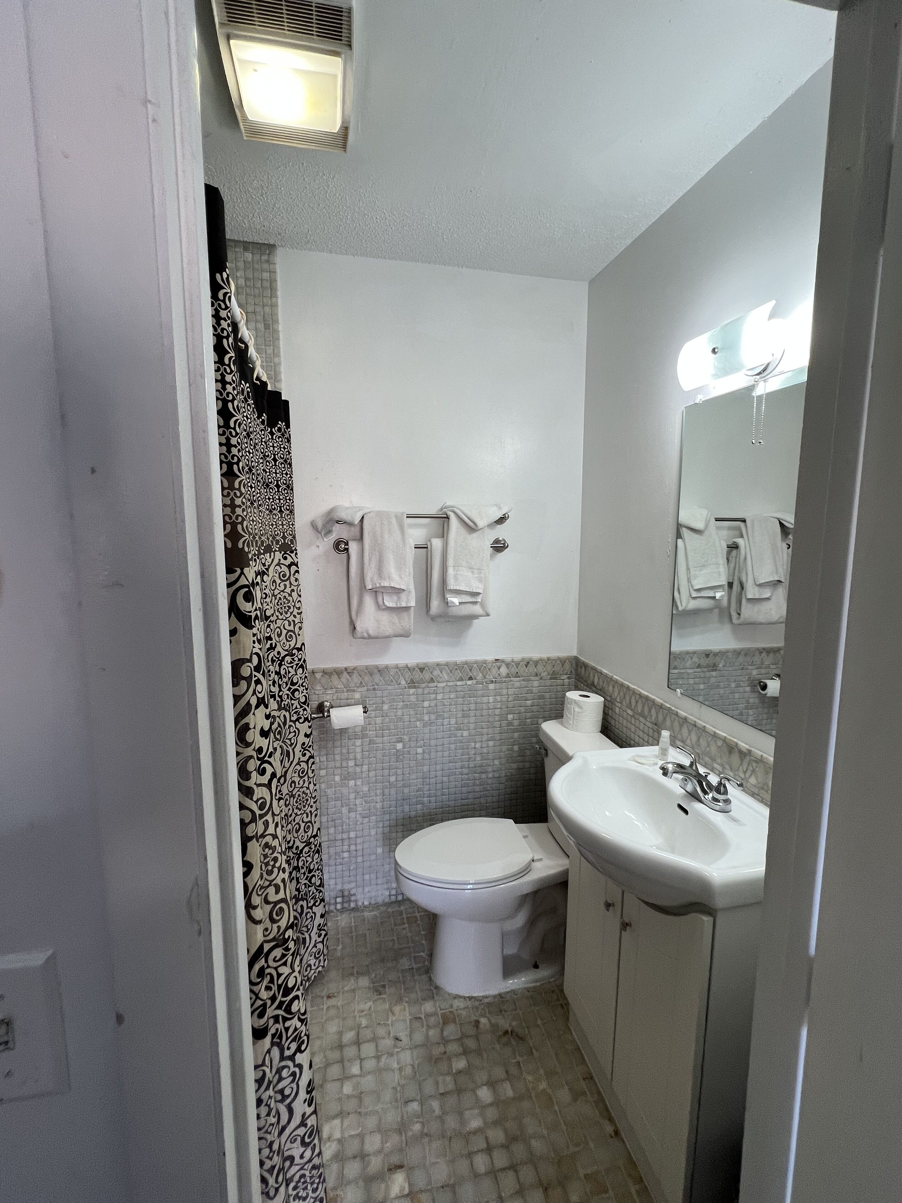 Un baño pequeño con inodoro, lavamanos y espejo.