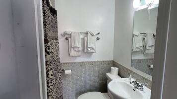 Un baño pequeño con inodoro, lavamanos y espejo.