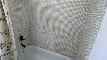 A bathtub with mosaic tile walls and a shower curtain.