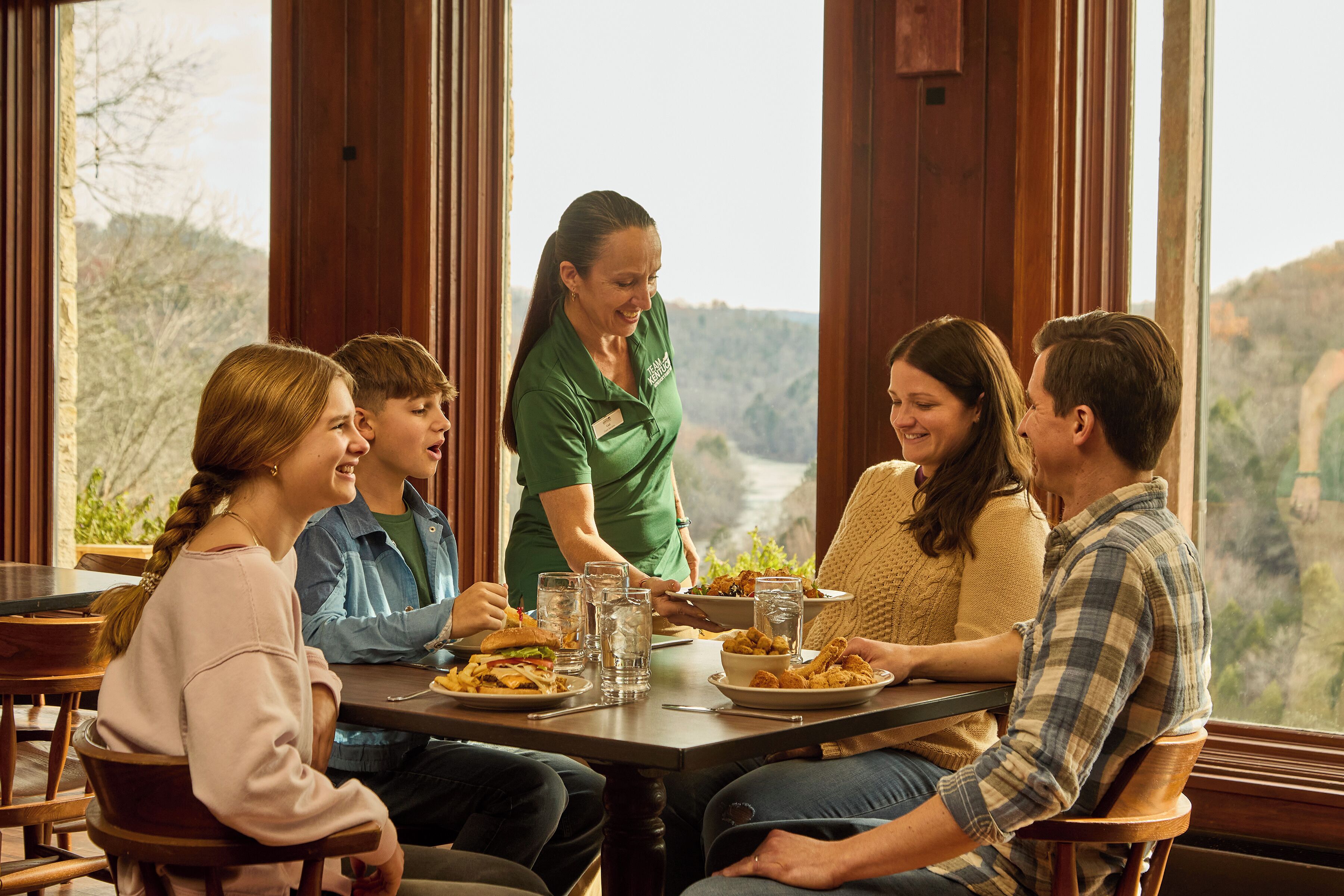 A group of people dining at a table with a view of the outdoors.