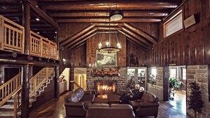 A spacious living room with a fireplace, leather sofas, and a wooden staircase.