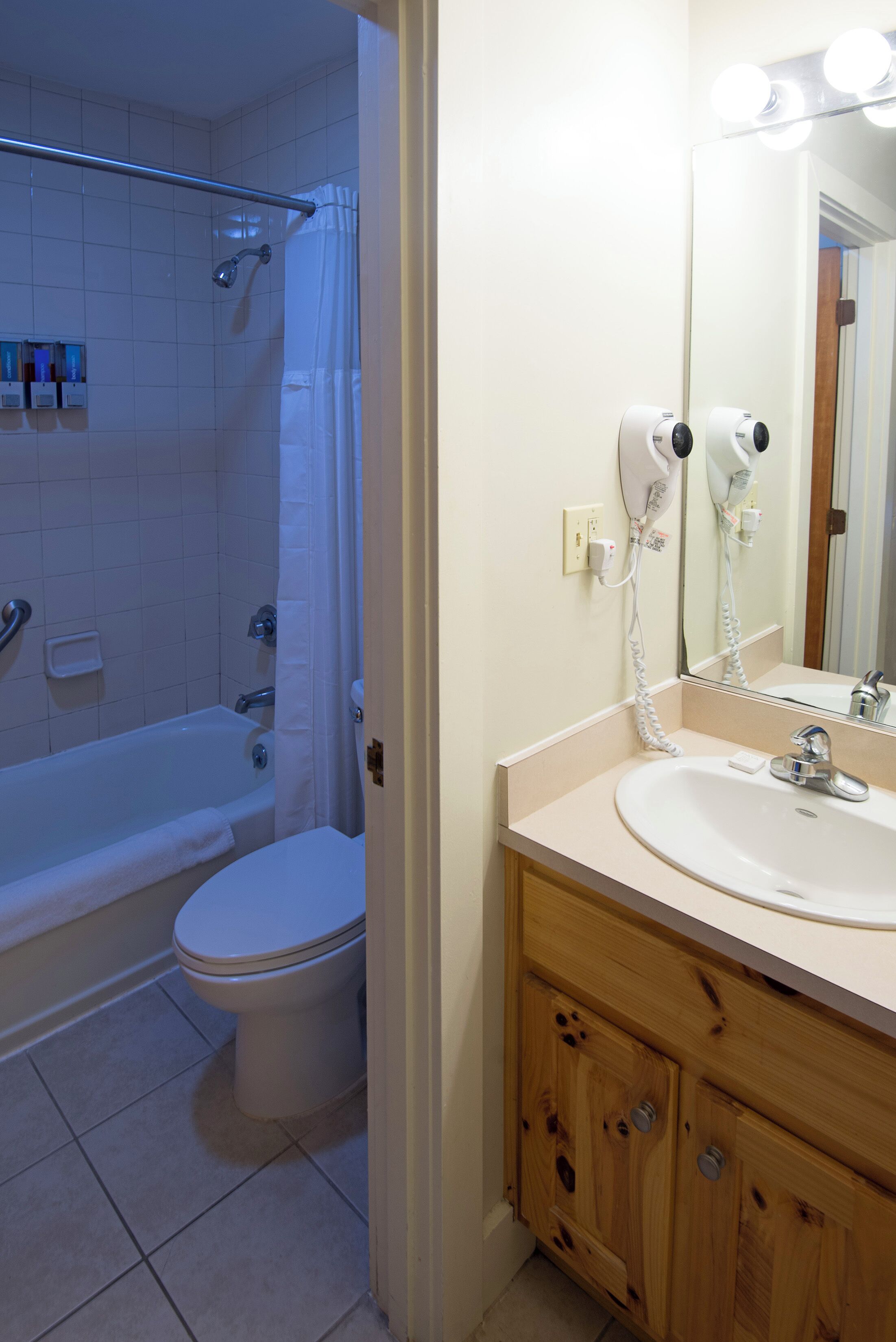 A bathroom with a bathtub, toilet, and a vanity with a sink and mirror.