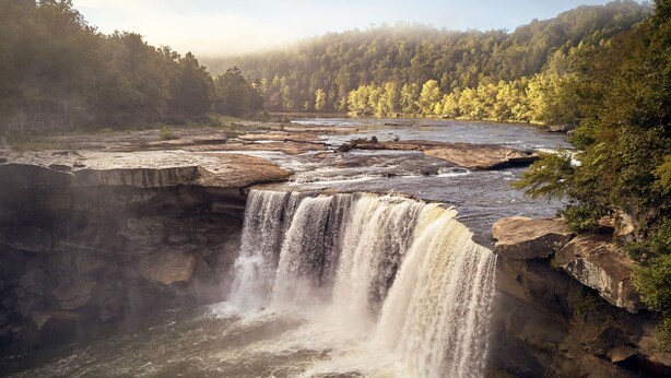 A waterfall cascading over rocky terrain with a forested backdrop.