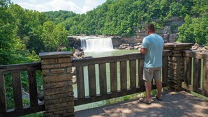A man standing on a stone bridge overlooking a waterfall.