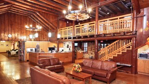 A spacious lobby with leather sofas, a wooden reception desk, and a staircase leading to an upper level.