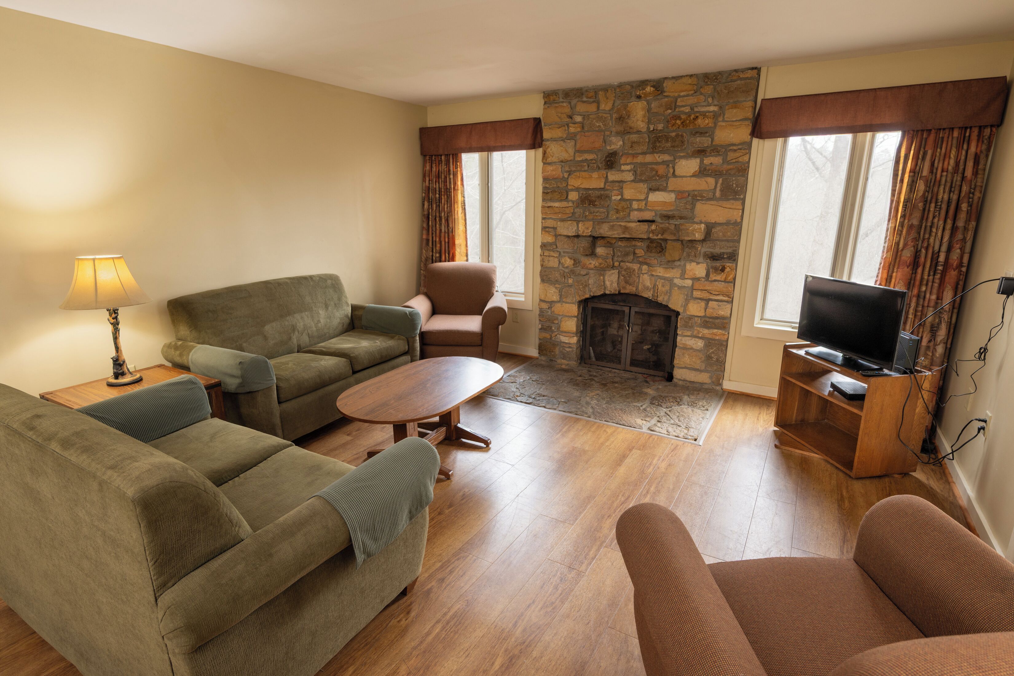 A living room with a stone fireplace, a television, and a sofa.