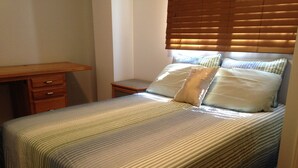 A bedroom with a bed, a wooden desk, and a nightstand. - Warbler's Roost Country Inn B&B (Unorganized Centre Parry Sound)