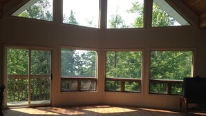 A spacious room with large windows, a wooden floor, and a balcony. - Warbler's Roost Country Inn B&B (Unorganized Centre Parry Sound)