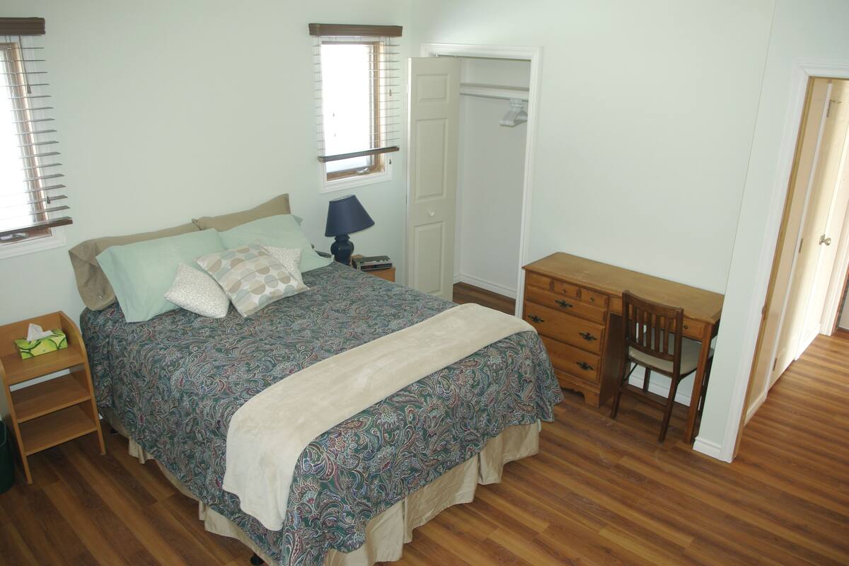 A bedroom with a bed, a desk, and a chair.