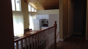 A kitchen with white cabinets, a refrigerator, and a microwave. There is a dining table with chairs. - Warbler's Roost Country Inn B&B (Unorganized Centre Parry Sound)
