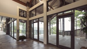 A spacious interior with large glass doors leading to an outdoor deck, stone accents, and a high ceiling.