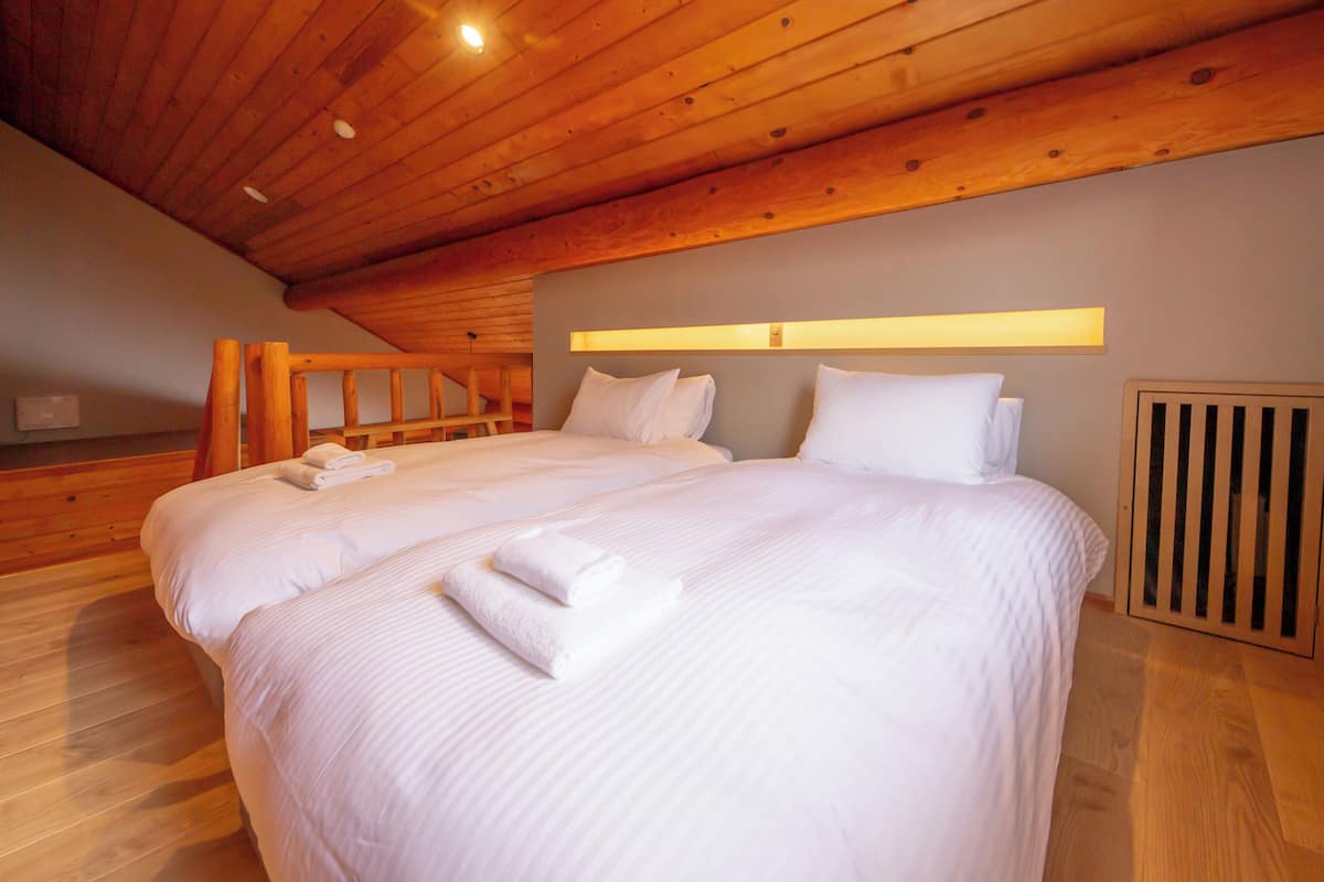 Ein großes Bett mit weißen Leinentüchern und einem hölzernen Kopfteil.
