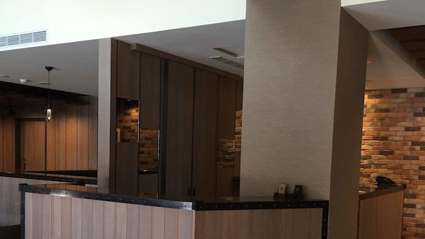 A modern kitchen with wooden cabinets, a central island, and a brick accent wall. - Just Live Inn Keelung (Keelung)