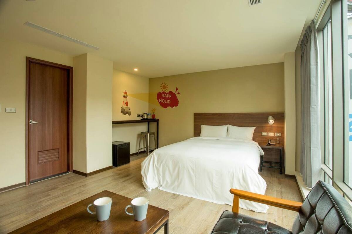 A hotel room with a bed, a desk, a chair, and a window.