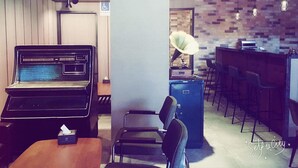 A modern bar area with a jukebox, bar stools, and a brick-patterned wall. - Just Live Inn Keelung (Keelung)