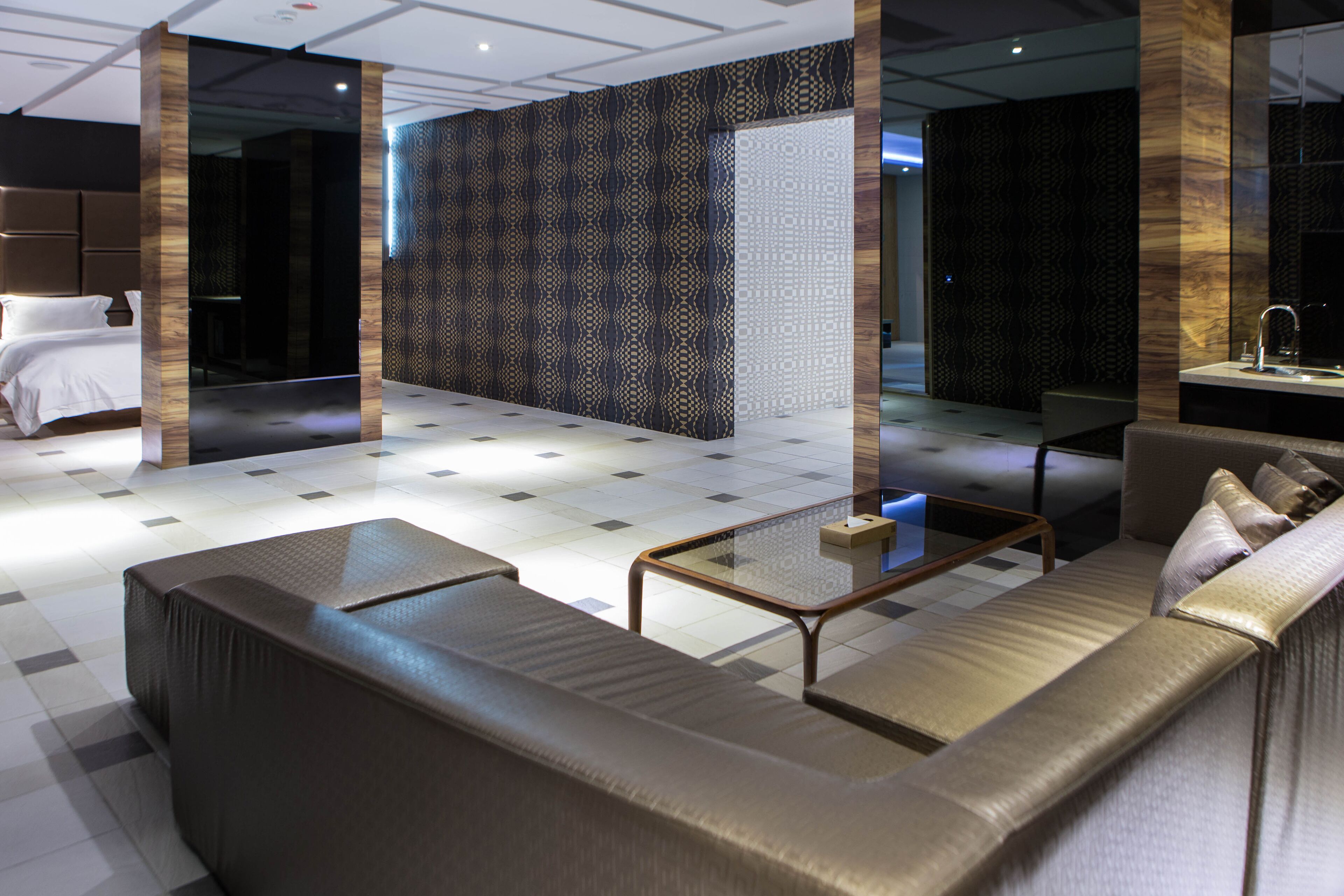 A modern hotel lobby with a large sofa, a coffee table, and a separate seating area with a sofa and a small table.