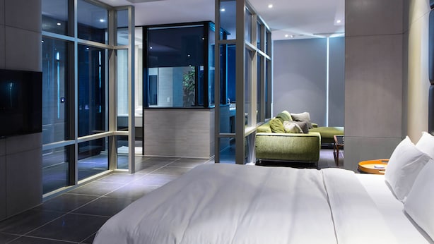 A modern hotel room with a large bed, a green sofa, and a TV mounted on the wall. - All-Ur Boutique Motel - Tai-Tung Branch (Taitung)