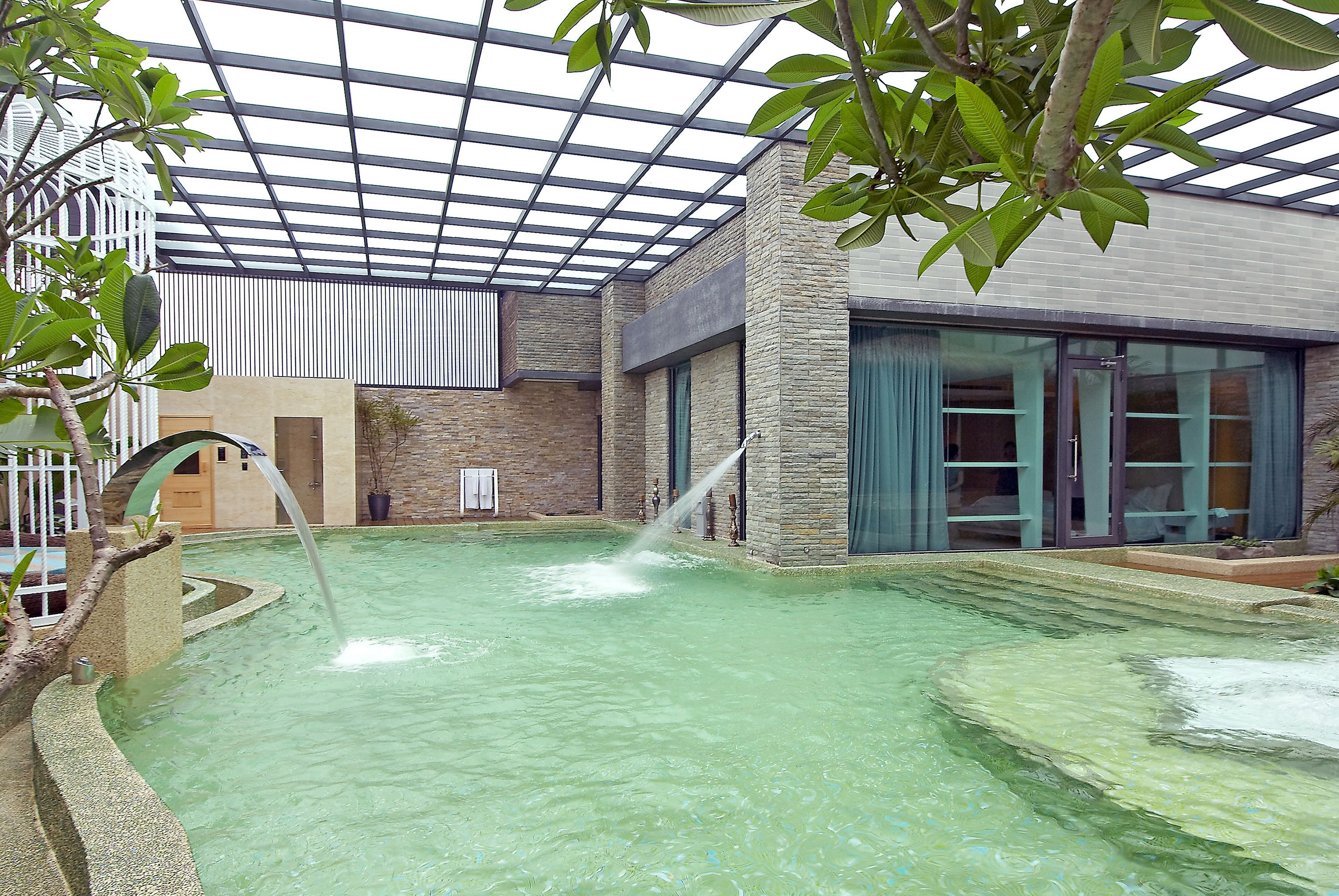 A spa area with a water feature, a covered seating area, and a building with large windows.